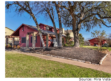 Mira Vista's red leasing office on a sunny morning. It is surrounded by green grass and tall oak trees