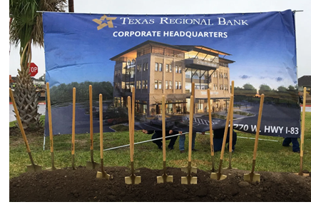 Shovels in the ceremonial "broke ground" in front of a banner depicting a rendering of the new Texas Regional Bank HQ.