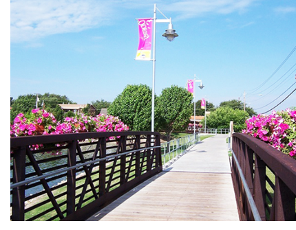 A foot bridge featuring pink flowers on the side, and banners that say "Odessa".