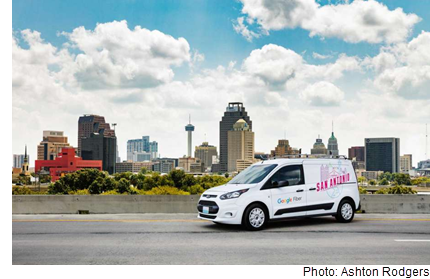 A google fiber van that says San Antonio, against the backdrop of the San Antonio skyline.