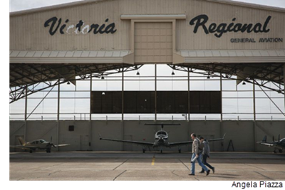 Two men walk in front of a hangar at Victoria Regional Airport.