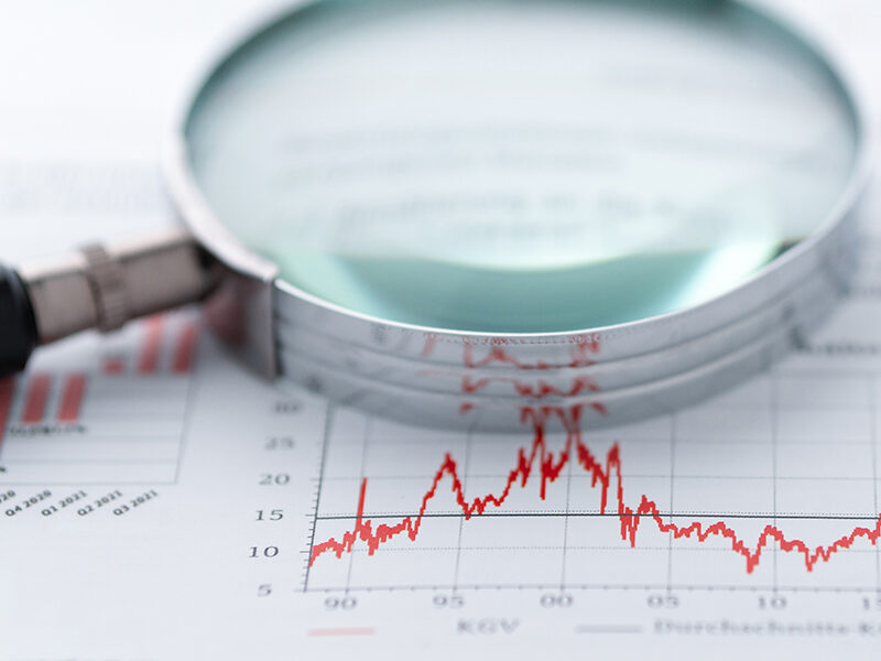 Magnifying glass and charts on paper symbolizing business and financial market. Studio shot in raw format taken with prime lens for best quality